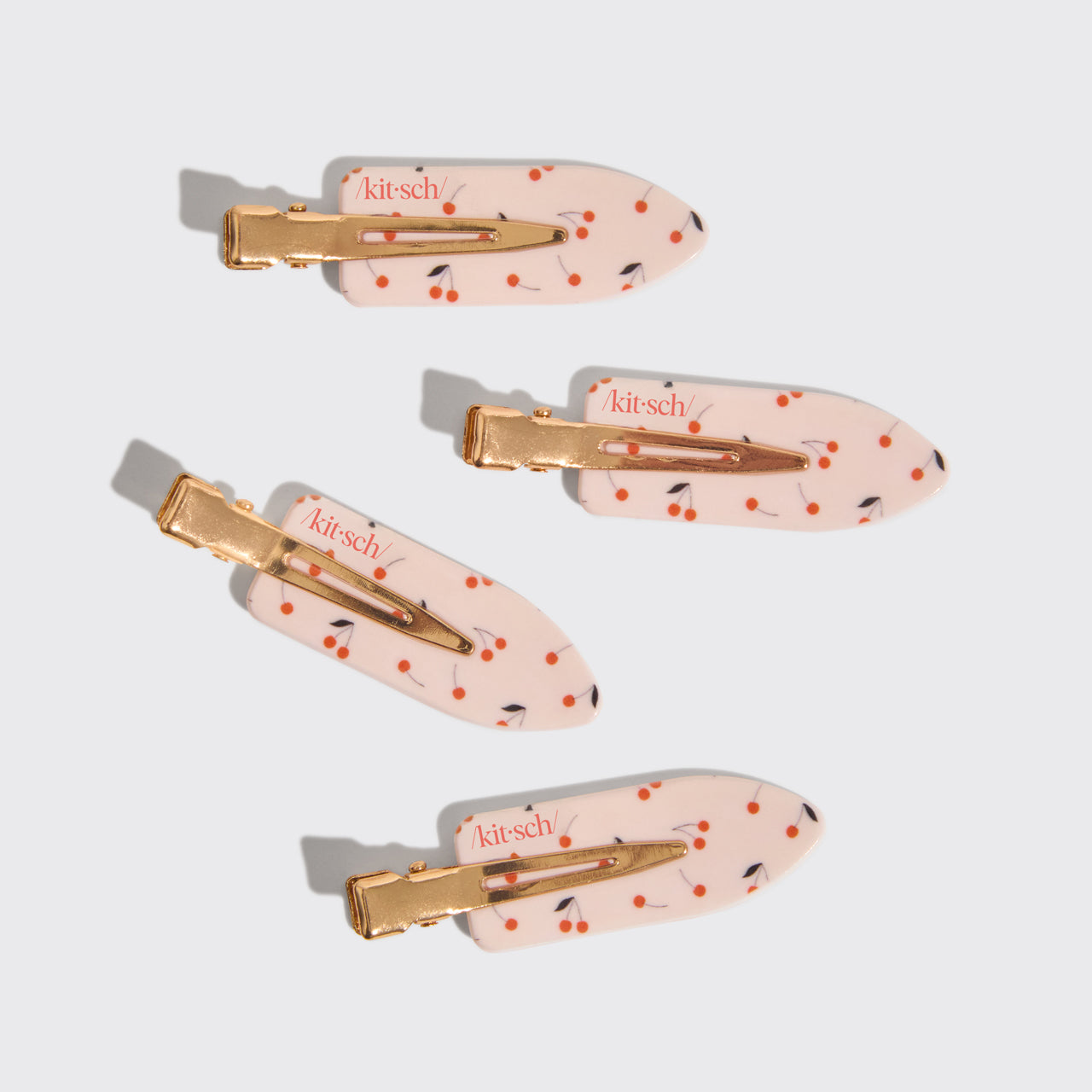 Four pink cherry print creaseless hair clips arranged on a gray background.