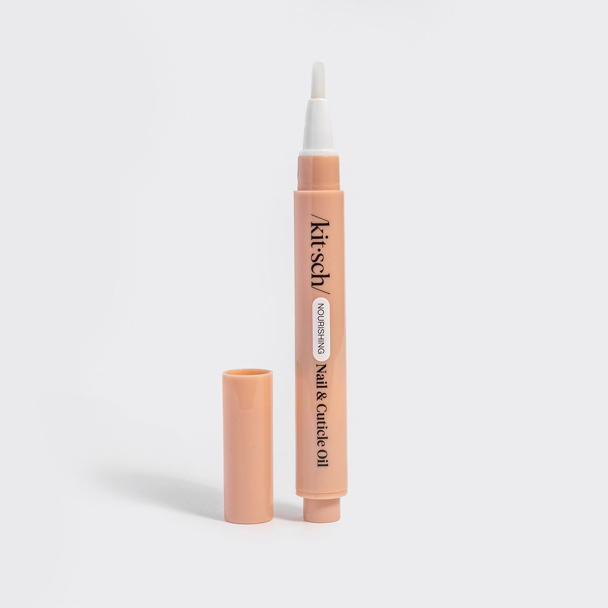 KITSCH Nourishing Nail & Cuticle Oil - Honey & Milk — uncapped peach pen standing upright with its white brush applicator, cap set beside it on a white background — brush-tip pen — delivers just the right amount of oil with no spills or waste
