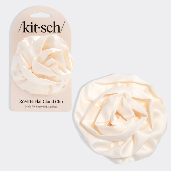 Cream-colored hair clip shaped like a soft rosette with layered, cloud-like petals. Shown next to beige packaging labeled “Kitsch” and “Rosette Flat Cloud Clip – Made from Recycled Materials.”