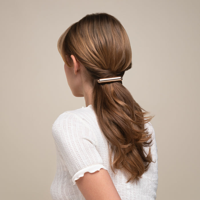 Woman with a ponytail held by a hair clip against a neutral background