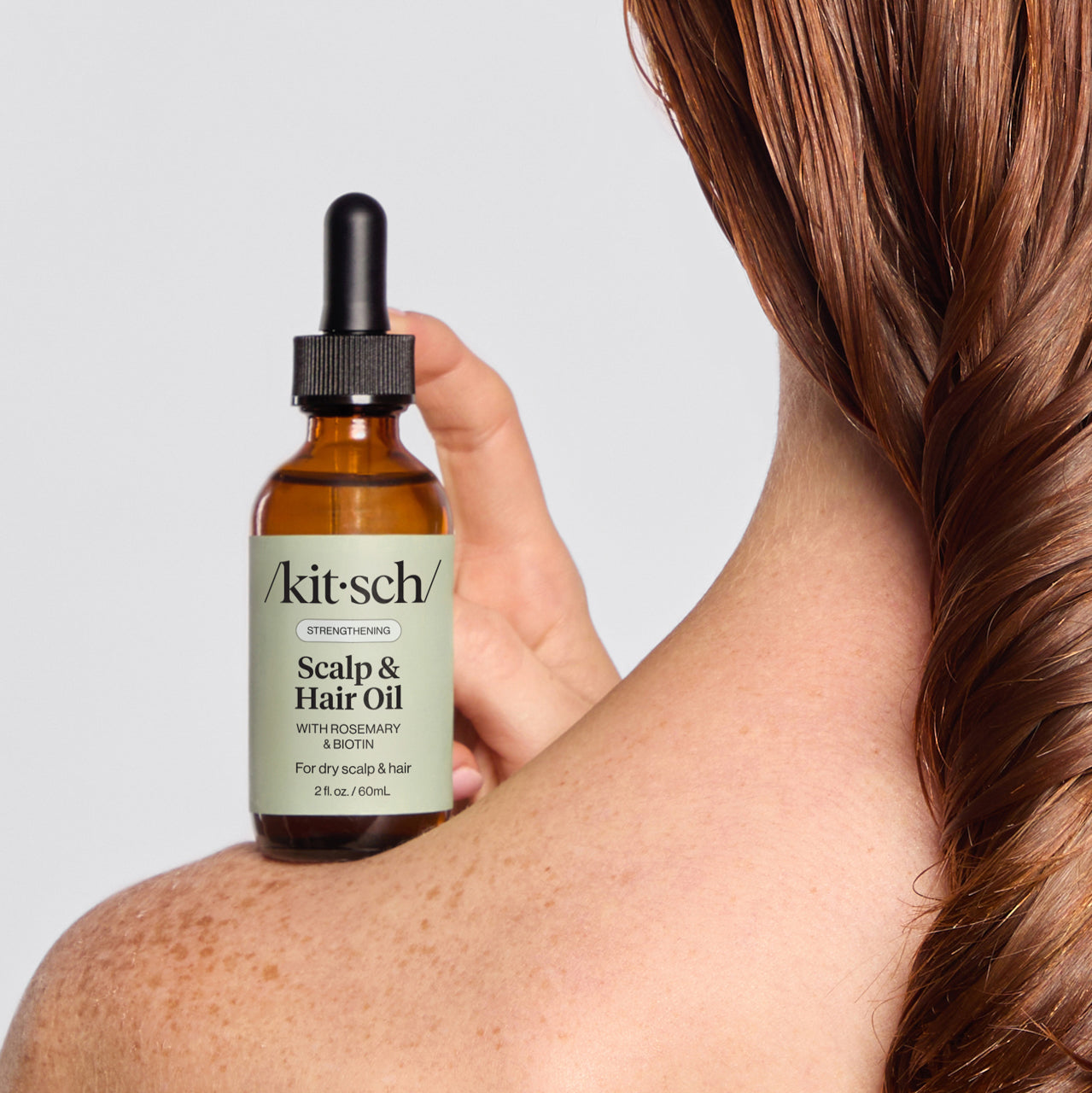 Model applying Strengthening Rosemary & Biotin Scalp & Hair Oil to the scalp before using the Terracotta Scalp Exfoliator