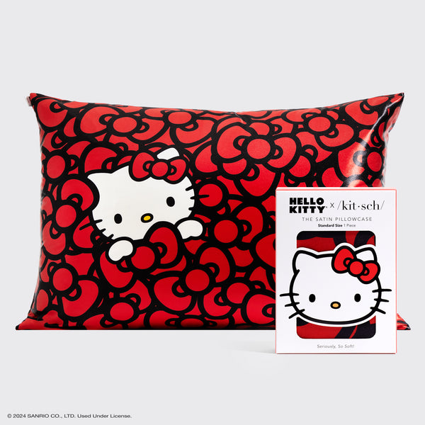 Kitsch x Hello Kitty satin pillowcase featuring Hello Kitty surrounded by red bows on a black background, shown with product packaging.