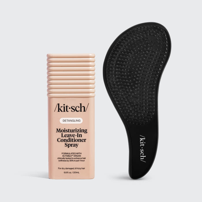 Kitsch Detangling Moisturizing Leave-In Conditioner Spray bottle in a pale peach-beige color next to a black silicone hair detangling mat on a light gray background.